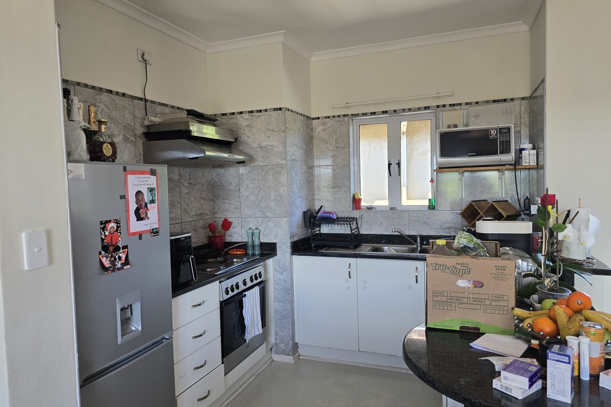 A functional kitchen featuring granite countertops, built-in cabinetry, a stainless steel oven, extractor fan, and a tiled splashback.