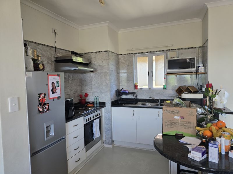 A functional kitchen featuring granite countertops, built-in cabinetry, a stainless steel oven, extractor fan, and a tiled splashback.