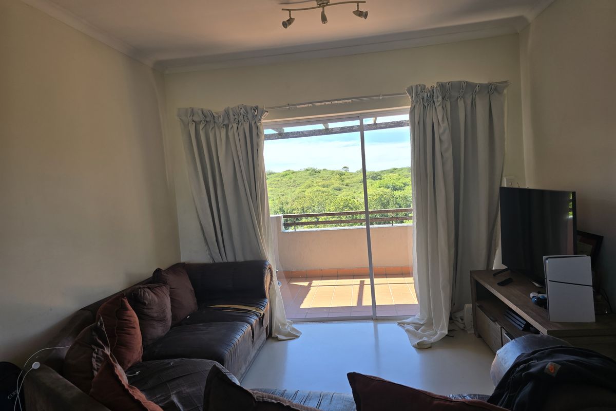 Living room featuring tiled flooring and a sliding glass door providing direct access to a private balcony with scenic views.