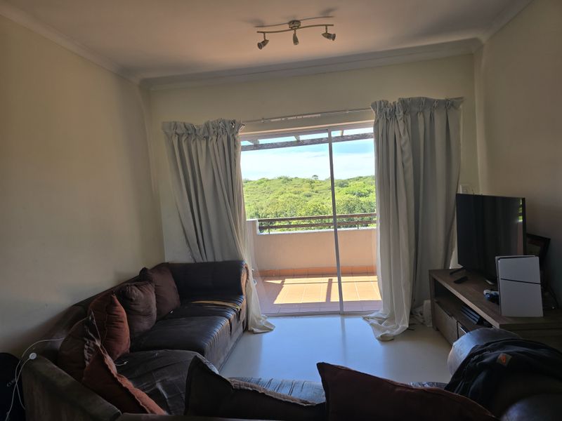 Living room featuring tiled flooring and a sliding glass door providing direct access to a private balcony with scenic views.