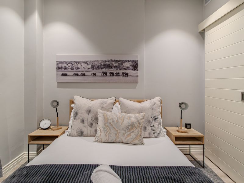 A well-maintained bedroom featuring neutral wall tones, recessed lighting, and a modern sliding door providing access to an en-suite bathroom.