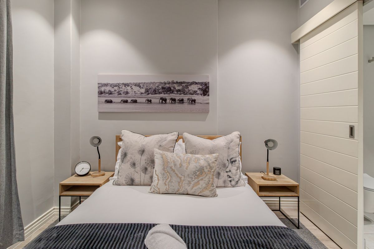 A well-maintained bedroom featuring neutral wall tones, recessed lighting, and a modern sliding door providing access to an en-suite bathroom.