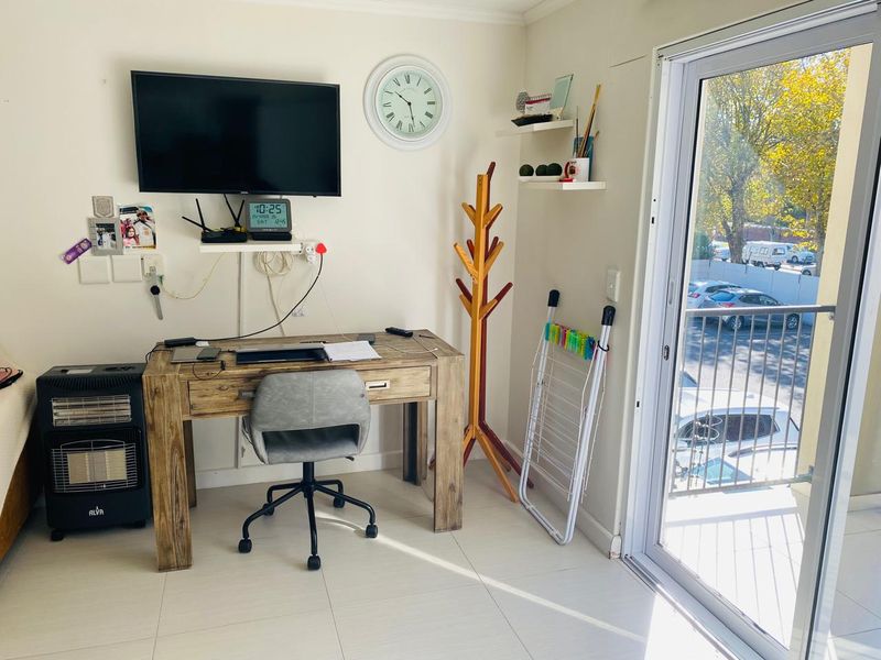 A functional living area featuring tiled flooring and a sliding glass door providing access to a balcony, offering natural light and outdoor connectivity.