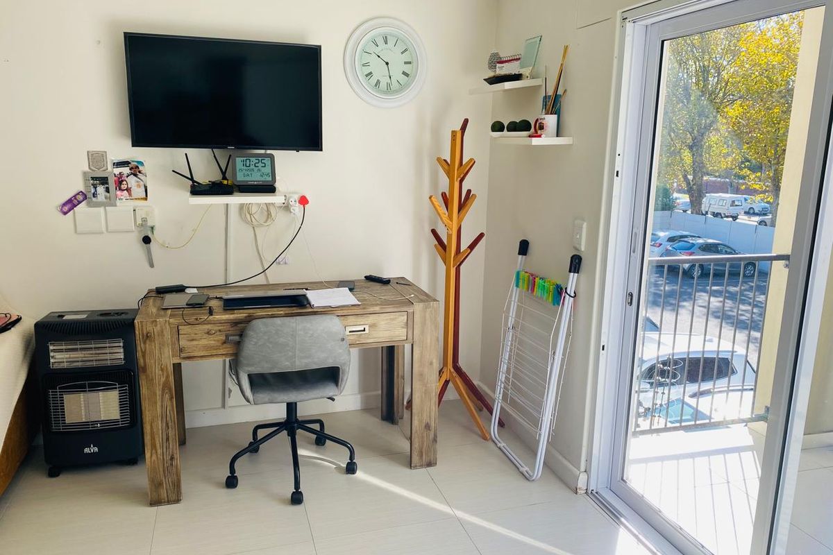 A functional living area featuring tiled flooring and a sliding glass door providing access to a balcony, offering natural light and outdoor connectivity.