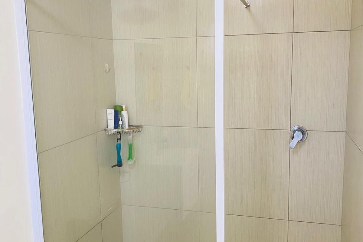 A modern bathroom featuring a walk-in shower with a glass screen, neutral wall tiling, and a tiled floor.