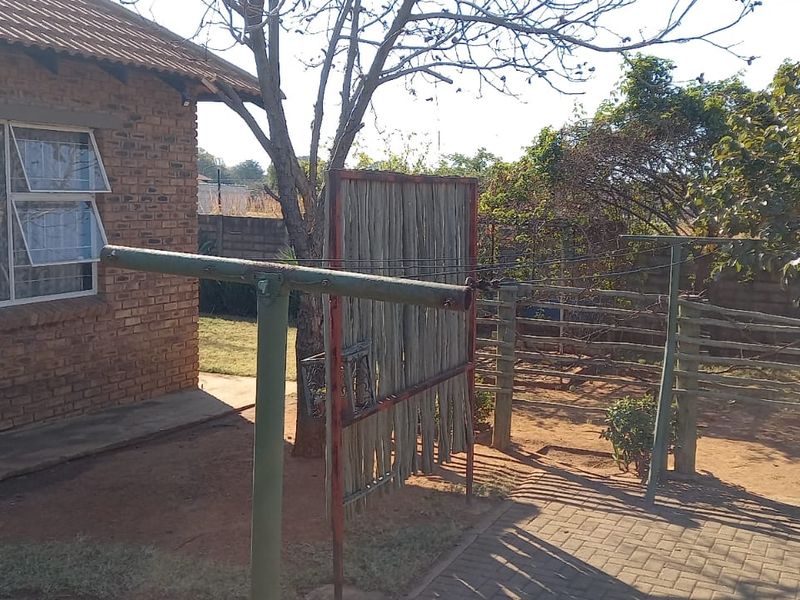 Rear exterior view of a face brick house featuring a paved area, perimeter wall, and outdoor washing line facilities.