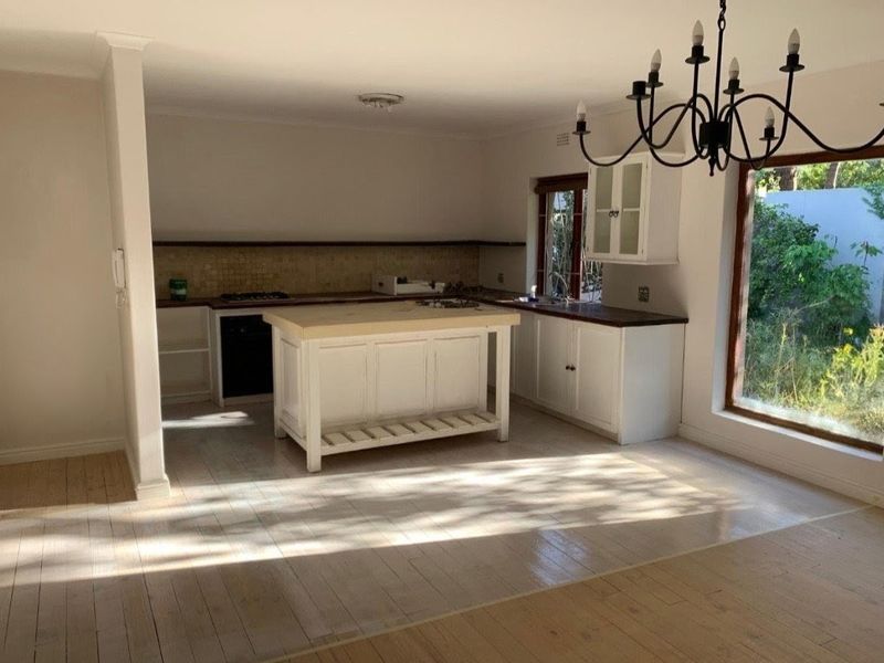 Spacious kitchen featuring a central island, built-in cabinetry, integrated oven and hob, and large windows providing natural light.