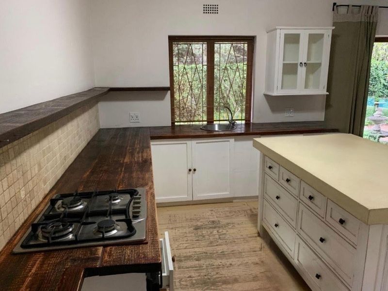 Kitchen featuring a gas hob, wooden countertops, tiled backsplash, and a central island with storage, offering a rustic aesthetic with functional workspace.