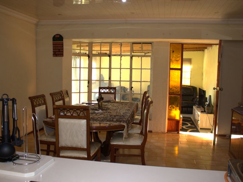 Open plan dining area featuring tiled flooring and direct access to an adjacent living space through traditional wooden framed glass doors.
