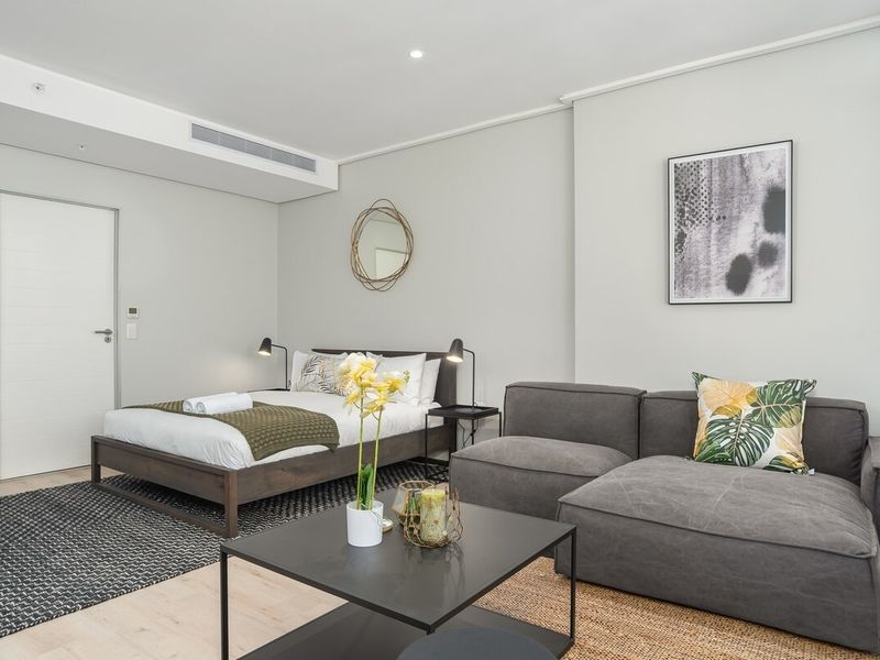 A modern, well-maintained open-plan studio apartment featuring neutral finishes, recessed lighting, and integrated ducted air conditioning.