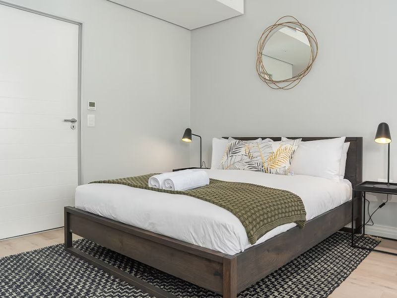 A well-maintained bedroom featuring neutral wall finishes, a modern flush panel door, and integrated electrical fixtures.