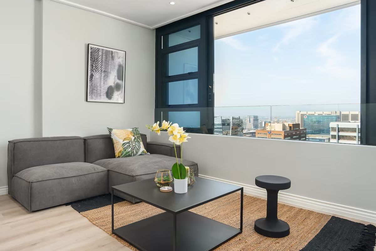Modern living area featuring large windows with expansive city views, glass balustrade, recessed lighting, and high-quality laminate flooring.