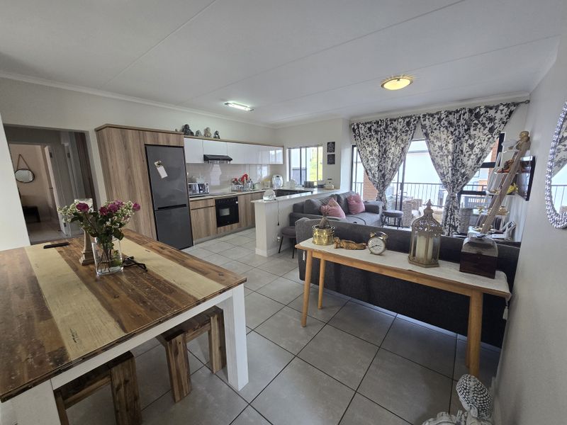 Spacious open-plan living area featuring a modern kitchen with built-in cabinetry, tiled floors, and direct access to a balcony through sliding doors.