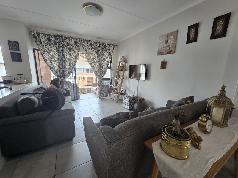 An open-plan living area featuring tiled flooring and a sliding glass door that provides access to an outdoor balcony space.