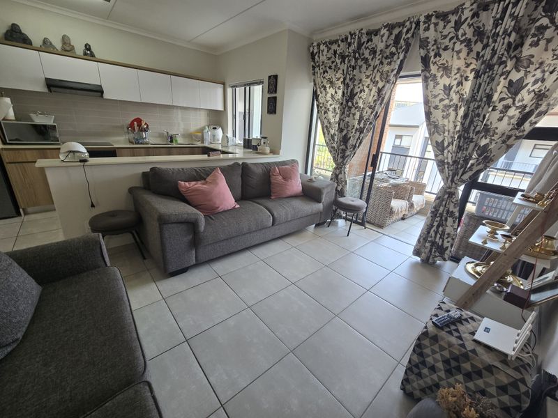 Open plan living area featuring a modern kitchen with built-in cabinetry and tiled flooring, leading directly to a private balcony through sliding glass doors.