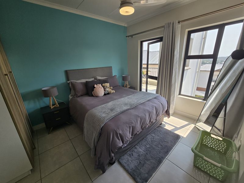 A well-maintained bedroom featuring tiled flooring, a ceiling fan, and direct access to a balcony through an aluminium door.