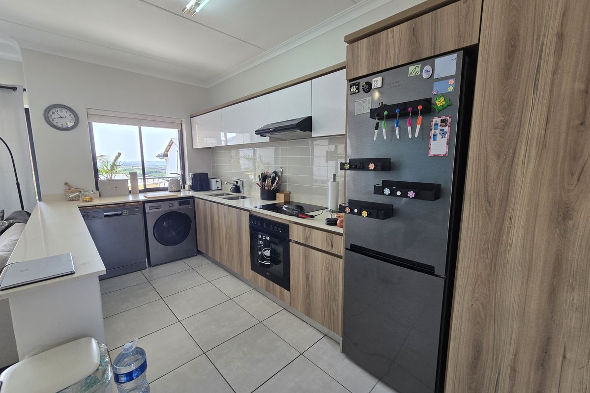 Modern kitchen featuring wood-grain cabinetry, integrated appliances, tiled flooring, and a sleek backsplash, offering a functional and contemporary cooking space.