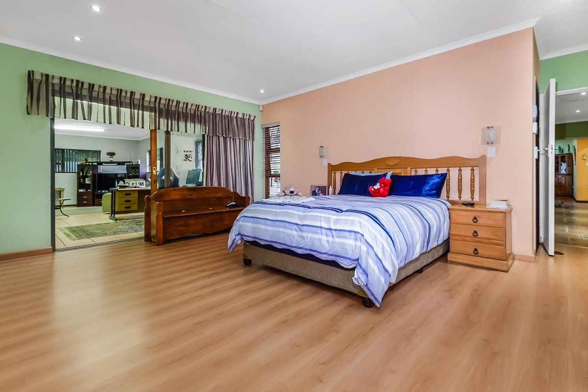 Spacious bedroom featuring laminate flooring, recessed lighting, and sliding glass doors that open into an adjacent living area.