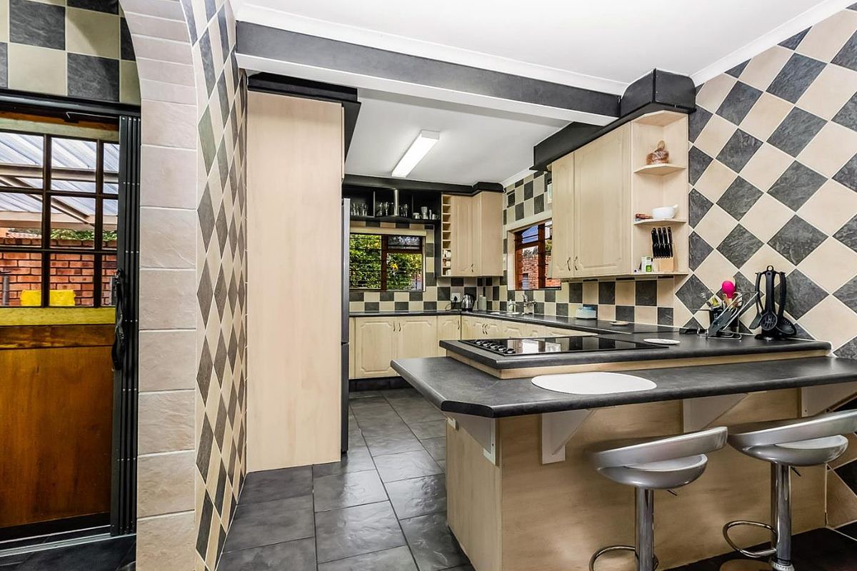 A functional kitchen featuring built-in cabinetry, a breakfast counter with integrated hob, and a distinctive diamond-patterned tiled backsplash.