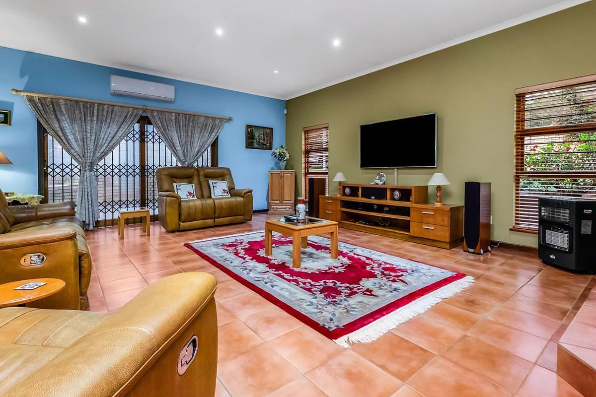 Spacious living room featuring tiled flooring, recessed downlights, and a split-system air conditioner, with sliding glass doors providing access to the exterior.