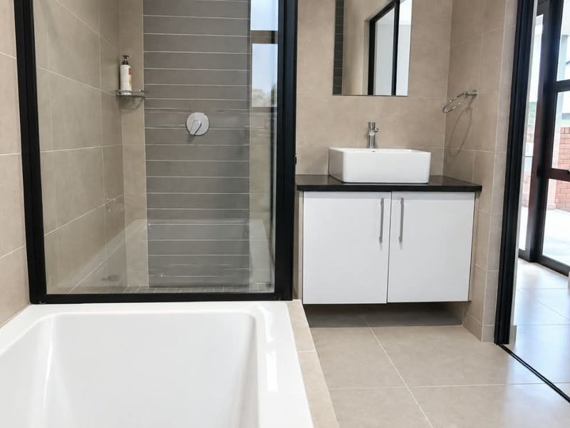 Modern bathroom featuring a walk-in shower with black frame, built-in bathtub, and a sleek vanity with a vessel sink.
