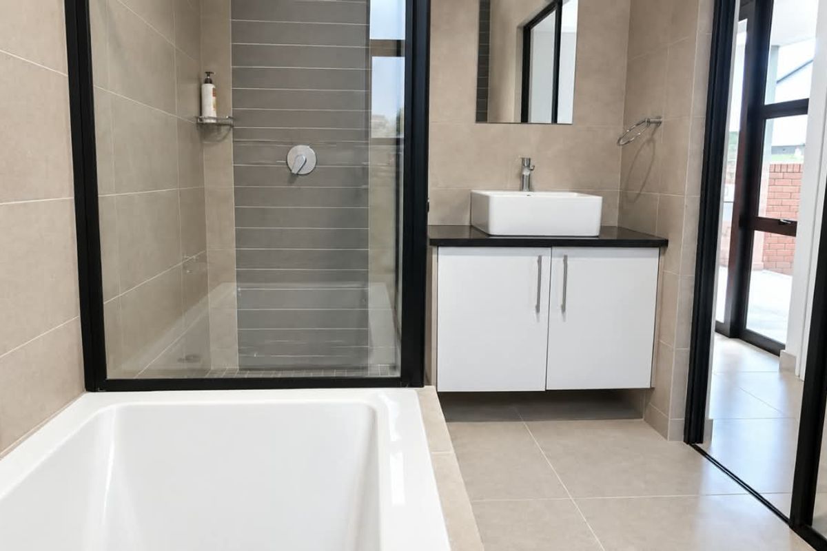 Modern bathroom featuring a walk-in shower with black frame, built-in bathtub, and a sleek vanity with a vessel sink.