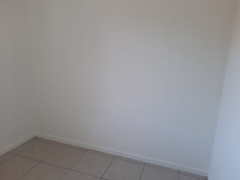 A simple, empty bedroom featuring neutral tiled flooring and clean white walls, providing a blank canvas for personalization.