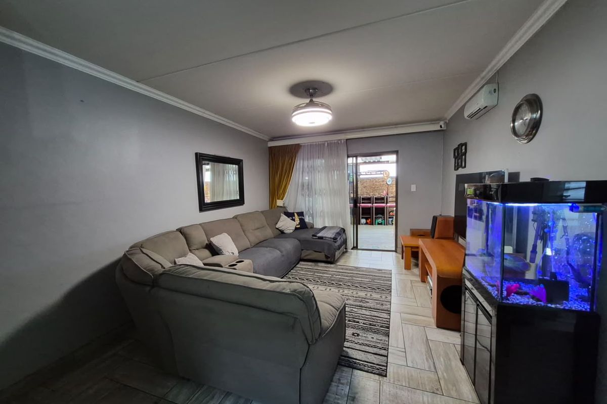 A comfortable living room featuring tiled flooring, a ceiling fan, and a split-system air conditioner, with direct access to an outdoor patio area.