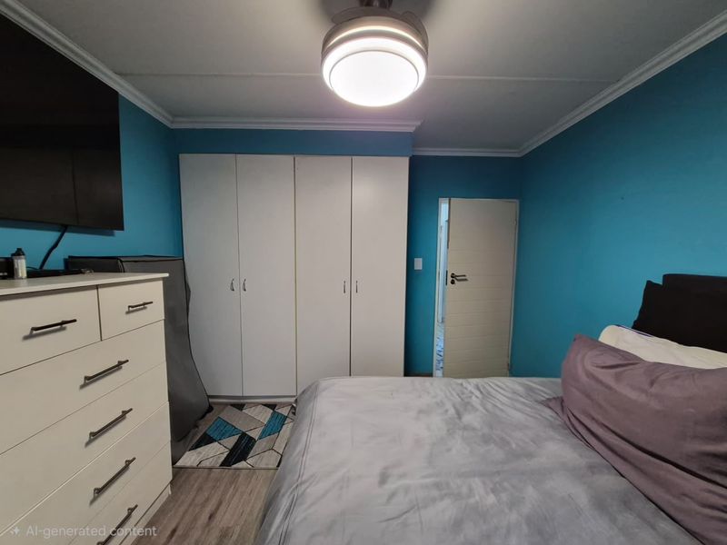 A bedroom featuring built-in cupboards, laminate flooring, and a ceiling fan, finished with blue walls and coving.
