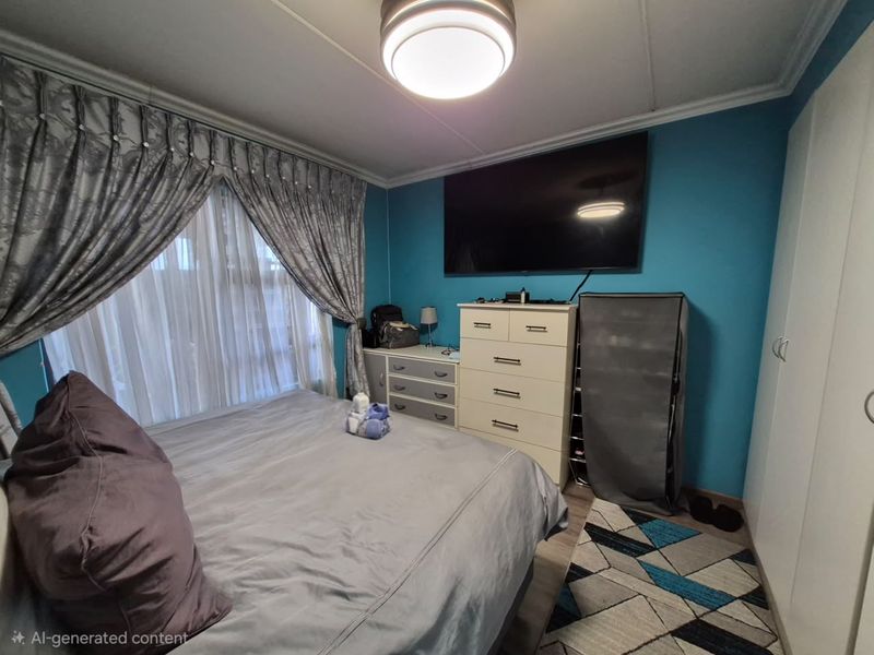 A bedroom featuring blue accent walls, a built-in wardrobe, and a central ceiling light fixture.