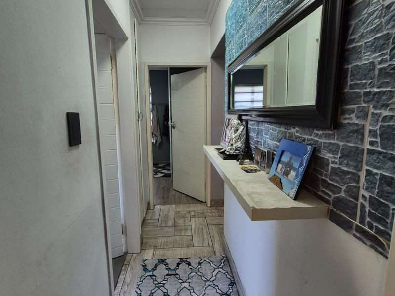 A functional hallway featuring tiled flooring, a built-in floating shelf, and decorative stone-effect wall cladding.
