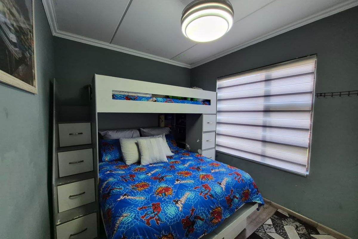 A bedroom featuring dark grey walls, crown molding, a ceiling fan, and modern roller blinds.