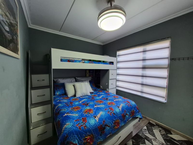 A bedroom featuring dark grey walls, crown molding, a ceiling fan, and modern roller blinds.