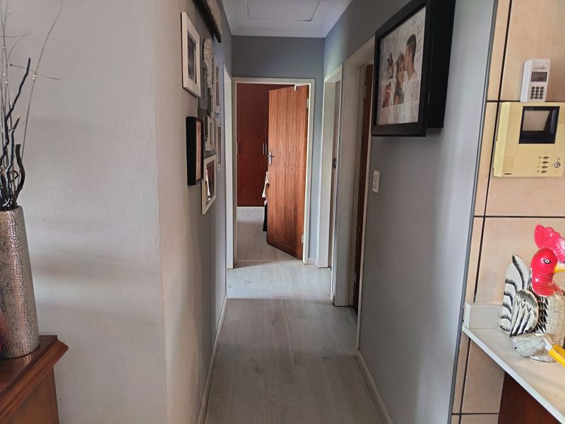 A functional hallway featuring light-toned laminate flooring, connecting multiple rooms with access to a built-in cupboard.