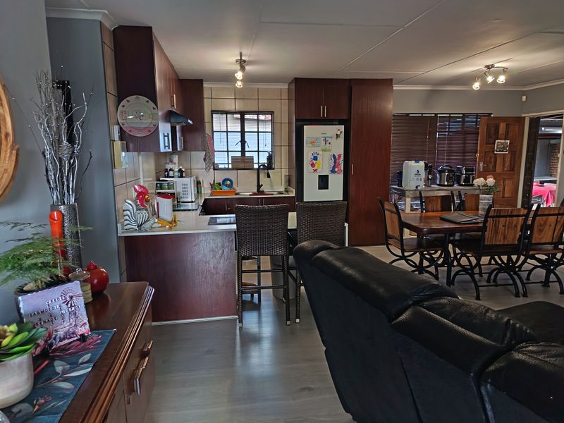 Open-plan living and kitchen area featuring dark wood cabinetry, laminate flooring, and a functional kitchen layout with integrated appliances.