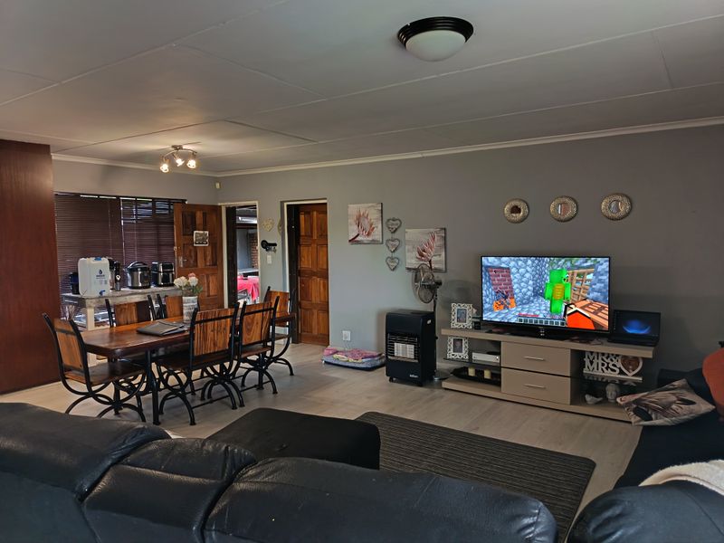 Open plan living and dining area featuring laminate flooring, neutral wall tones, and wooden door finishes, creating a functional and connected family space.