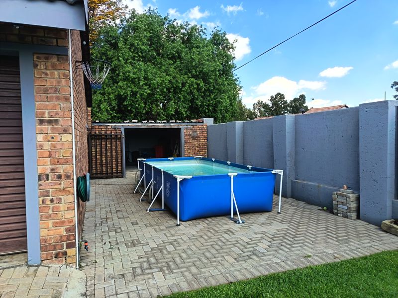Outdoor area featuring brick paving, a perimeter wall, and access to a garage structure.