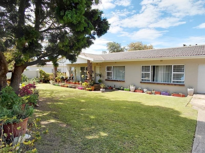 Front view of a single-story residential house featuring a well-maintained lawn, tiled roof, and aluminium window frames with a paved driveway.