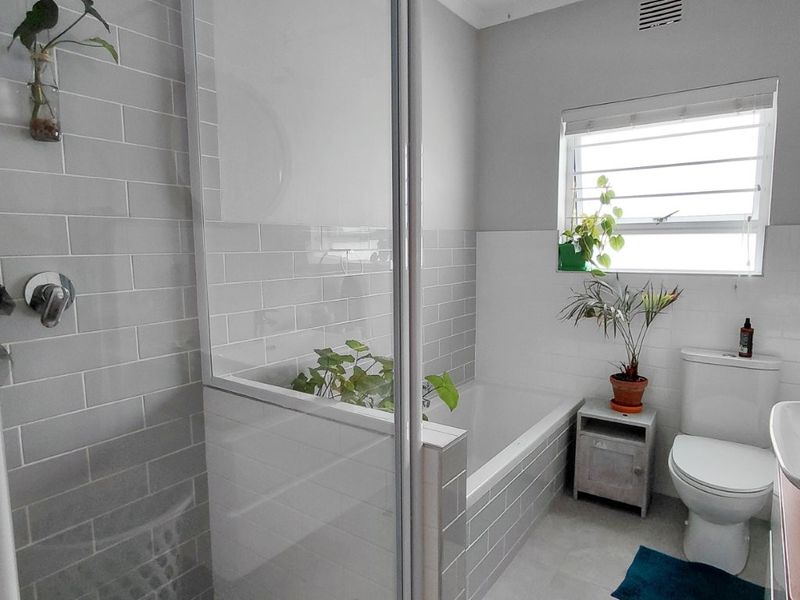 Modern bathroom featuring a glass-enclosed shower, built-in bathtub, subway tile finishes, and a louver window for natural ventilation.
