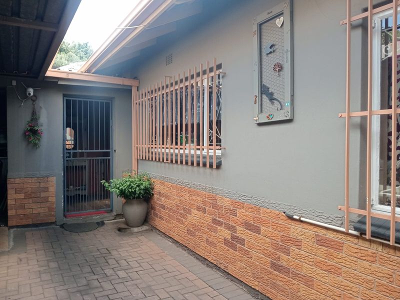 A paved rear courtyard area featuring a security gate entrance and exterior walls with brick cladding and security bars on the windows.