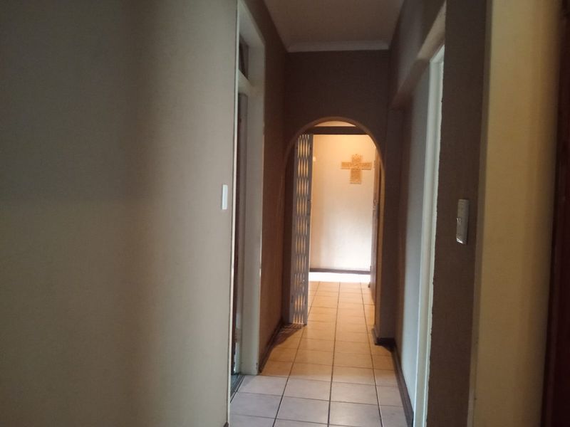 A functional interior hallway featuring tiled flooring and an arched transition leading to adjacent rooms.