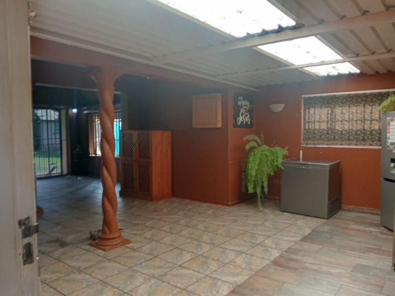 A covered outdoor patio area featuring tiled flooring, a decorative column, and translucent roof panels, providing a versatile space for outdoor living.