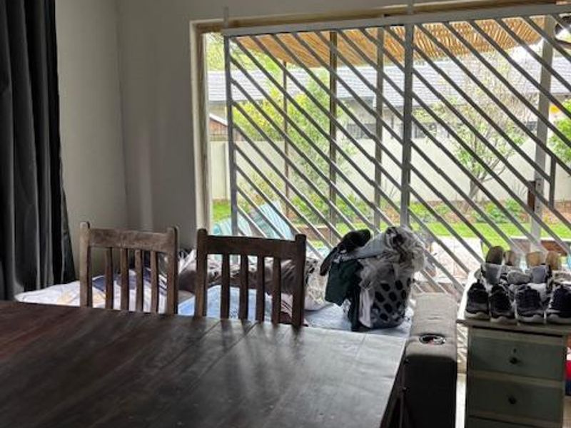 Living area featuring tiled flooring and a large sliding glass door with security gate, providing access to the outdoor space.