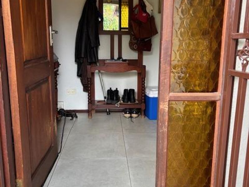 A functional entrance foyer featuring tiled flooring and a classic timber door with decorative textured glass panels.