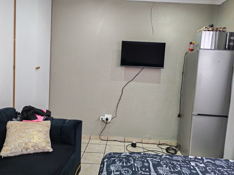 A living area featuring tiled flooring and a built-in wardrobe, with visible wall-mounted electrical cabling.