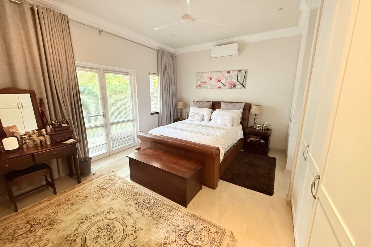 A well-maintained bedroom featuring tiled flooring, built-in cupboards, a ceiling fan, and a split-system air conditioner with direct access to an outdoor area.