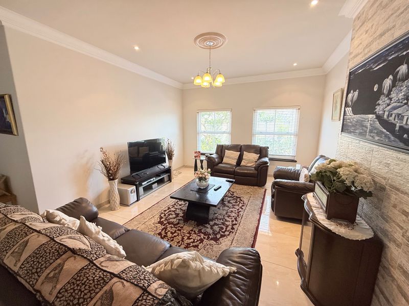 Spacious living room featuring polished tiled flooring, a decorative ceiling rose, and a textured stone feature wall, creating a comfortable and inviting atmosphere.