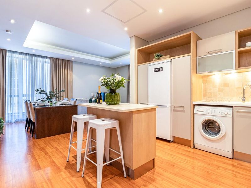 Modern open-plan living area featuring a compact kitchen with integrated cabinetry, a central island, and seamless flow into the dining space.