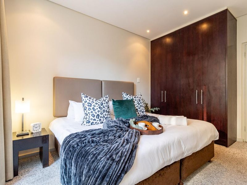 A well-maintained bedroom featuring dark wood built-in cupboards and recessed downlighting, creating a warm and functional living space.