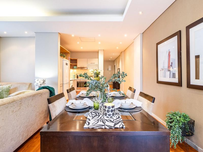 An open-plan living and dining area featuring hardwood floors, recessed ceiling lighting, and a modern kitchen with built-in cabinetry and integrated appliances.